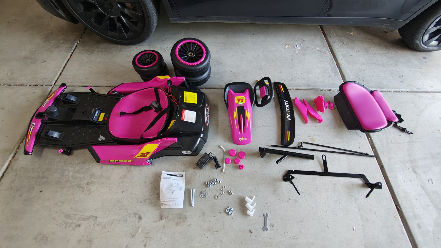 Pink electric drift cart laid out in parts before assembly