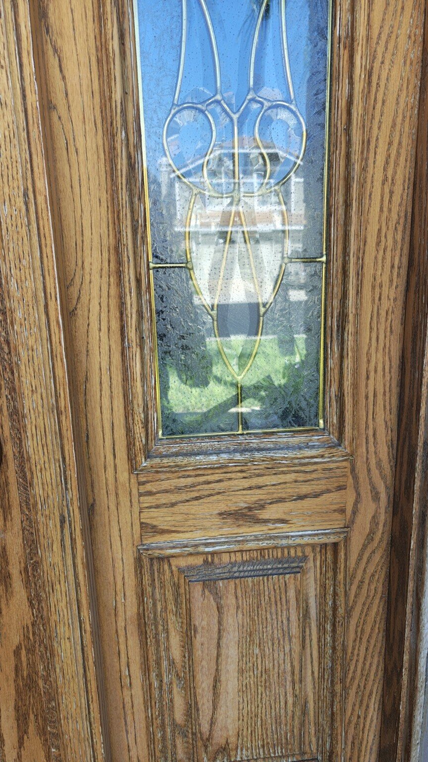 Close view of the worn finish around the oak door glass
