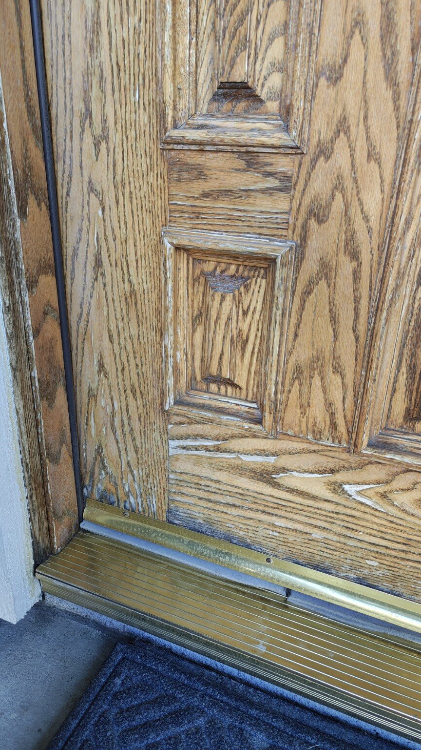 Close view of weather damage along the bottom of the oak entry door