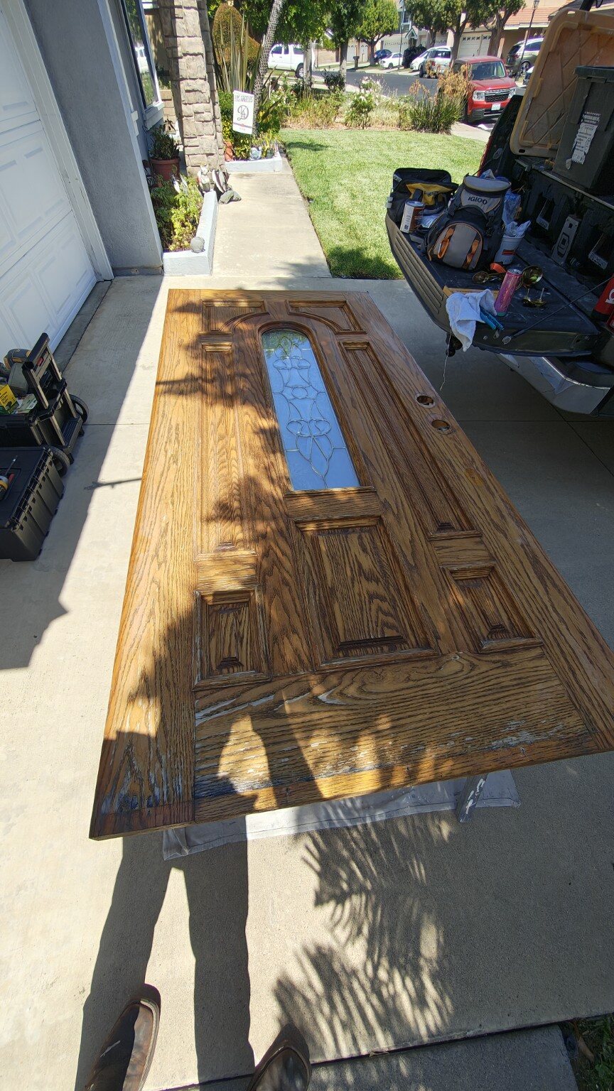 Oak entry door laid flat during the cleaning and refinishing process