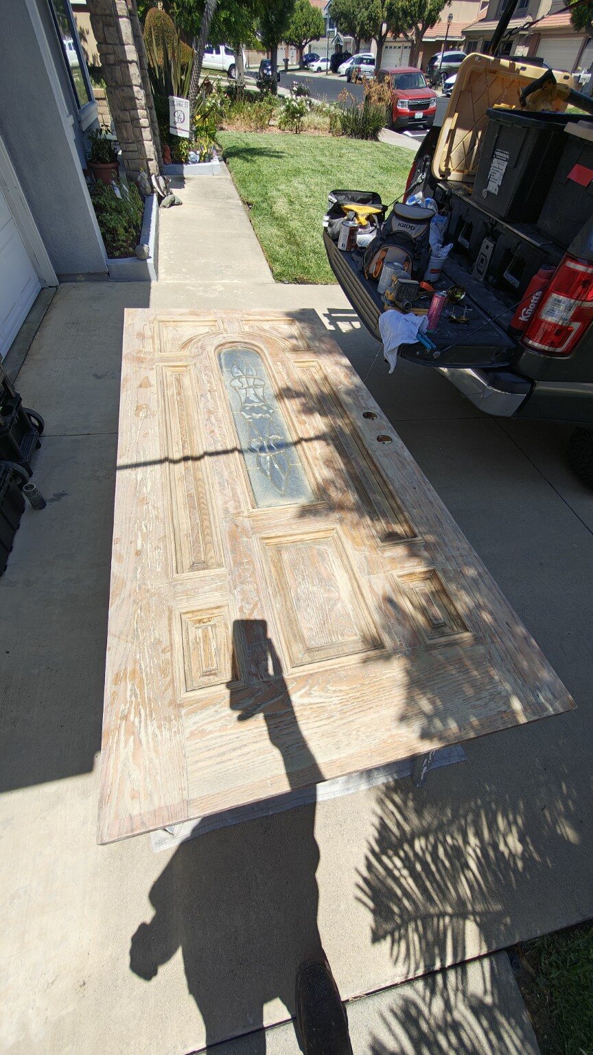 Oak entry door during surface preparation for refinishing